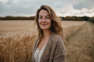 Wall Mural - Portrait of a satisfied woman in her 30s wearing a chic cardigan over quiet countryside landscape