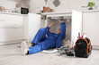 © Pixel-Shot - Mature female plumber installing sink in kitchen