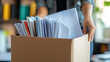 © Papon - A business person unpacking a shipping box filled with documents in a modern office environment