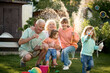 © Iuliia Versta/Stocksy - Granny and grandpa playing with their grandchildren on a backyard