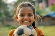 © Anjali - Indian girl athlete smiling  holding soccer ball on field.