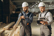 © anatoliycherkas - Builders inspecting wooden plank in modular building industry factory