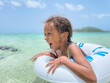 © Anya Brewley Schultheiss/Stocksy - Child in a inflatable ring with a huge smile on her face as she swims