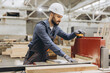 © anatoliycherkas - Carpenter operating woodworking machine in factory for modular building