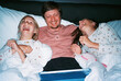 © Tanya Yatsenko/Stocksy - Father with daughters watching video and laughing