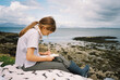 © Tanya Yatsenko/Stocksy - A girl on the beach writing in a notepad