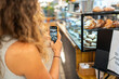 © Alvaro Lavin/Stocksy - Woman taking photo of pastry display in cafe using smartphone