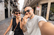© Alvaro Lavin/Stocksy - Happy couple taking a selfie while eating street food
