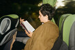 © Duet Postscriptum/Stocksy - A young woman reads a book while traveling by bus
