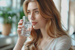 © Chalita - Female entrepreneur enjoys a glass of clean drinking water while working in a modern office.