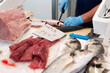 © Hernandez & Sorokina/Stocksy - Anonymous fish market seller cleaning the fish