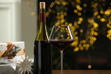 Canvas Print - Red wine and gift boxes against blurred Christmas lights, closeup. Bokeh effect