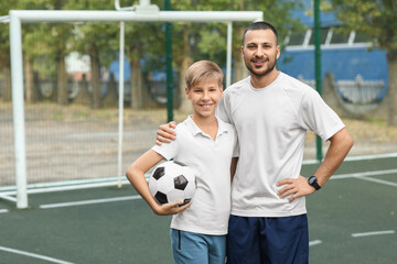 Canvas Print - Father and his son with ball on soccer pitch