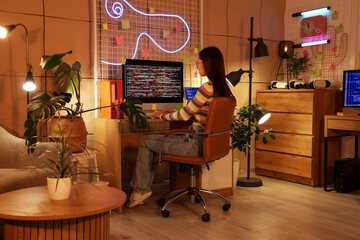 Wall Mural - female programmer working with computer in office at night
