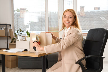 Wall Mural - Mature businesswoman taping box in office on moving day