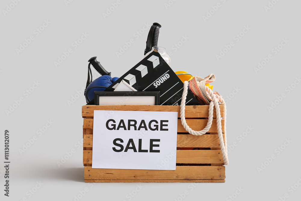 Box of unwanted stuff for garage sale on light background