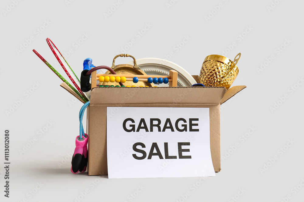 Box of unwanted stuff for garage sale on light background