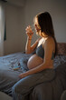 © Artem Zhushman/Stocksy - A pregnant woman drinks water in bed