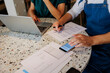 © BONNINSTUDIO/Stocksy - Business people analyzing financial documents at restaurant