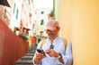 © Lupe Rodriguez/Stocksy - tourist using mobile phone in Genoa city, Italy