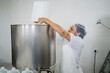 © J Esteban Berrío/Stocksy - Food factory worker pouring ingredients into a processing tank