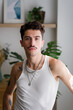 © mahalo studio/Stocksy - man with tattoos posing in a modern apartment