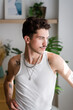 © mahalo studio/Stocksy - man with tattoos and silver necklaces is looking away
