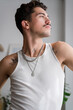 © mahalo studio/Stocksy - man with tattoos and jewelry posing indoors