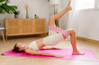 © mahalo studio/Stocksy - woman doing glute bridge exercise with resistance band at home