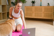 © mahalo studio/Stocksy - woman connecting to online fitness class with her dog nearby