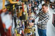 © Serhii - A man in a hardware store choosing a tool