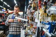 © Serhii - A male buyer in a modern hardware store. A large selection of tools and various household and construction goods