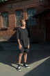 © Basil Pind/Stocksy - Young man standing in sunlight near a brick building
