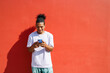 © Artem Podrez/Stocksy - Man Leaning Against Red Wall Using Phone