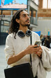 © Jimena Roquero/Stocksy - Traveling man in train station checking train schedule on screen