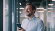 © yenart - Man smiling while looking at his smartphone in an office setting.