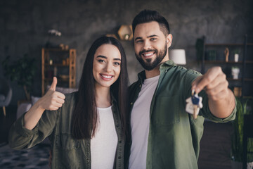 Wall Mural - Photo of sweet happy married lady guy wear khaki shirts rising keys showing thumb up indoors room home house