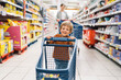 © Santi Nuñez/Stocksy - Happy young boy pushing a shopping cart in a grocery store aisle