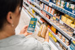 © Santi Nuñez/Stocksy - Woman using smartphone app to check product information at grocery sto