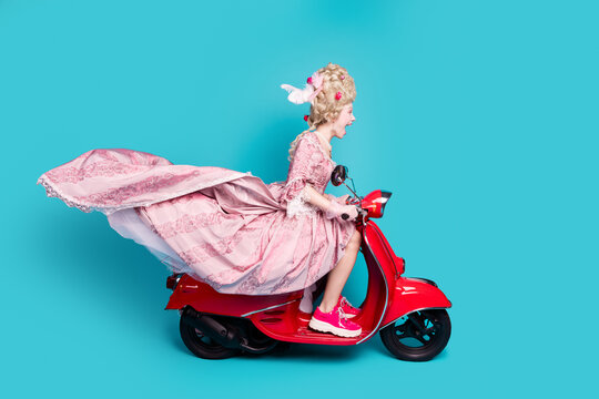 Photo of positive charming lady princess driving fast moped scooter isolated on blue color background