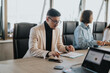 © qunica.com - A multicultural group of business people engaged in an important meeting, reviewing documents and discussing strategies in a modern office setting.