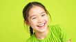 © velikiyzayats - Bright Young Girl Smiling Happily in Green Shirt on Vibrant Yellow Background, Perfect for Kids' Clothing or Happy Themed Designs