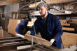 © JackF - Male worker in uniform carries board from storage location to processing location. Selects planks for furniture manufacture