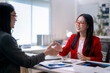 © Apichat - Two women shaking hands in a business setting