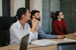 © qunica.com - A group of multicultural business people attentively participating in a professional meeting around a desk. They are focused and engaged, highlighting teamwork, collaboration, and communication skills