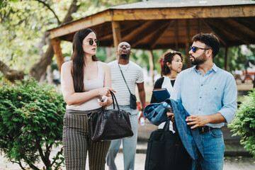 Wall Mural - A group of diverse business people engage in a casual conversation outdoors. The setting is a park, providing a relaxed atmosphere, with trees and greenery in the background.