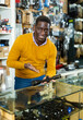 © JackF - African-american man seller standing at counter in arms shop and presenting rifle telescope.