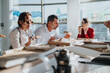 © qunica.com - A diverse group of business employees share a pizza lunch in a bright, modern office setting. Their relaxed conversation and casual atmosphere emphasize team bonding and workplace camaraderie.