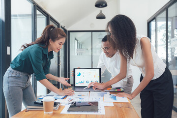 Wall Mural - Collaborative Analysis: A diverse team of professionals gathers around a laptop, examining data and charts, engaging in a collaborative brainstorming session.