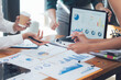 © Kritdanai - Strategic Business Meeting: Hands actively engaged in analyzing data charts and graphs during a collaborative work session.  Focus on detail and teamwork in a modern office environment.